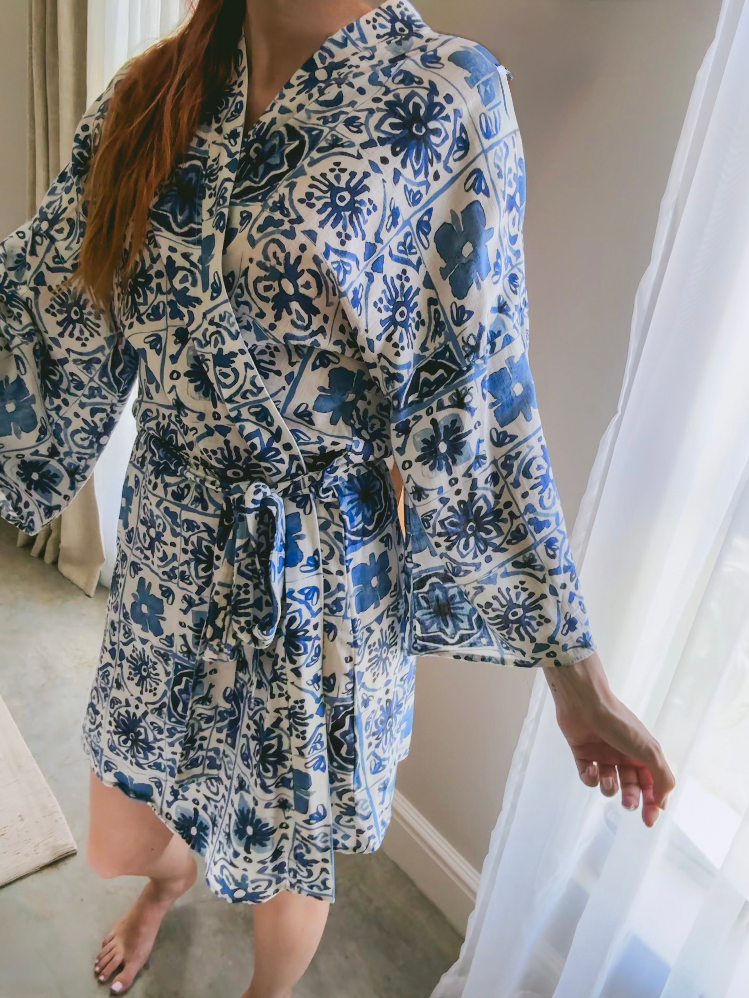 Person wearing a blue and white Moroccan tile print kimono wrap gown made from Ecovero Viscose Linen with separate waistband tie.
