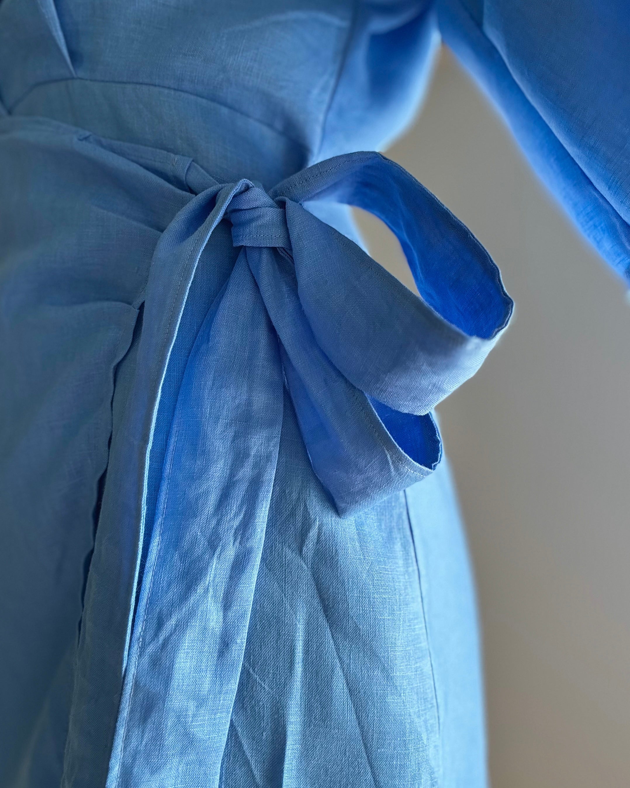 Close-up of a marina blue dress made from pure linenwith a bow detail.
