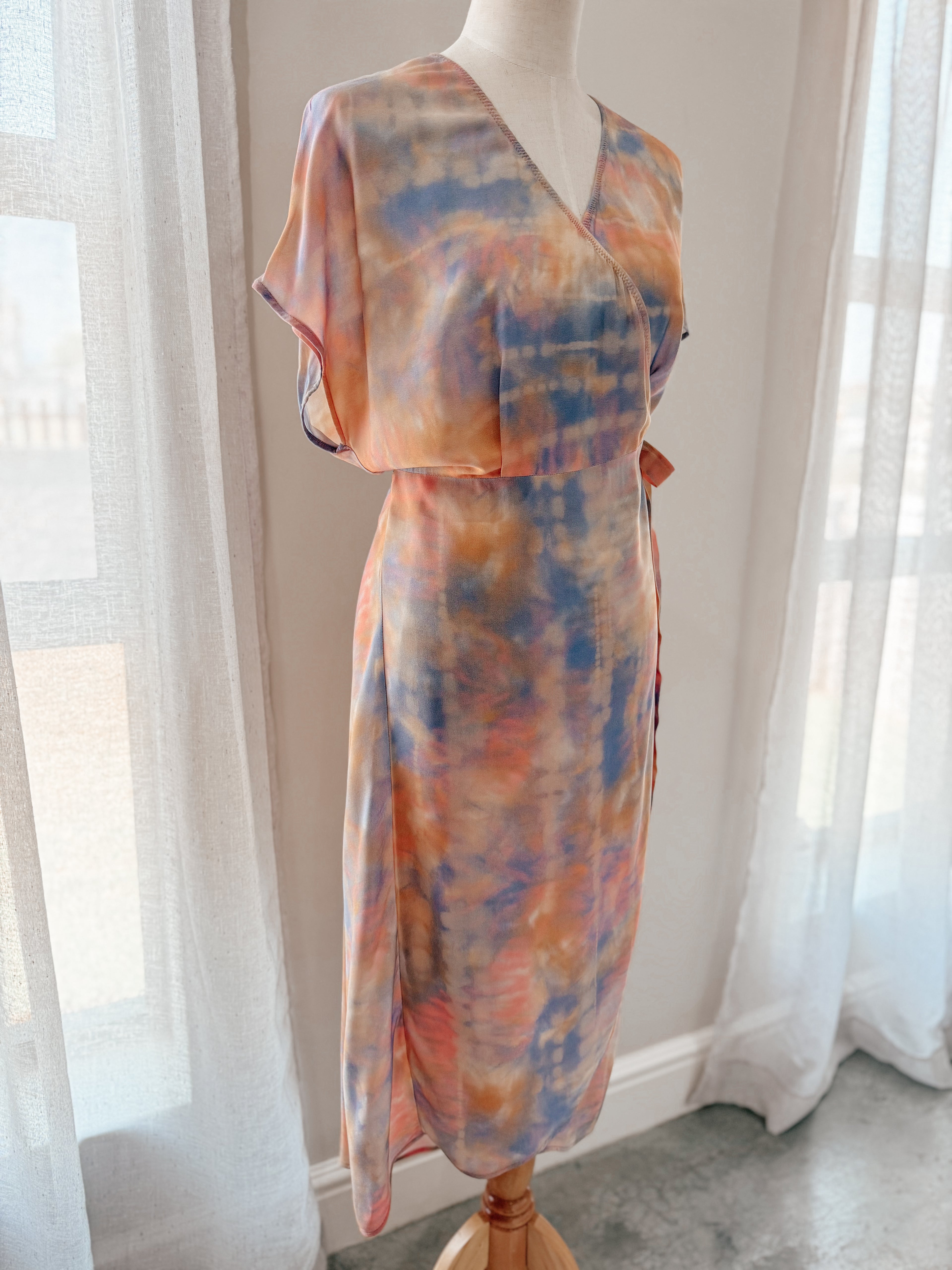 Tie-dye print midi wrap dress in soft watercolour hues with relaxed grown on cap sleeve on mannequin.