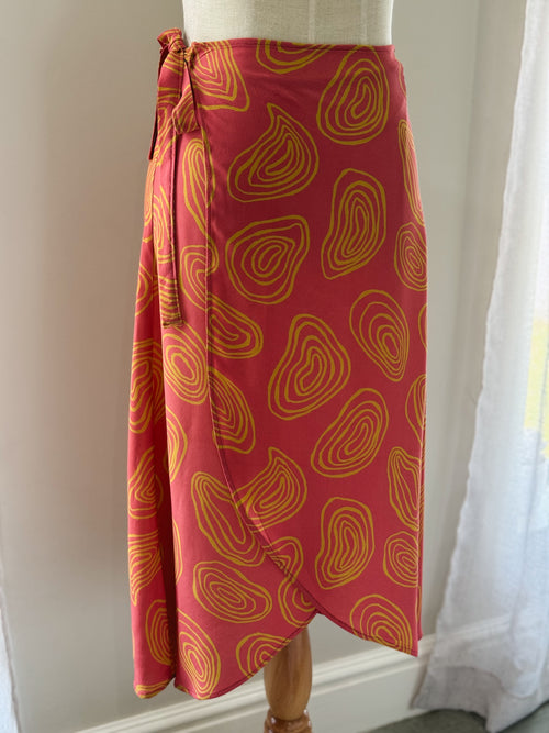 Coral colour midi wrap skirt with yellow squiggle patterns made from Ecovero viscose and displayed on a mannequin.