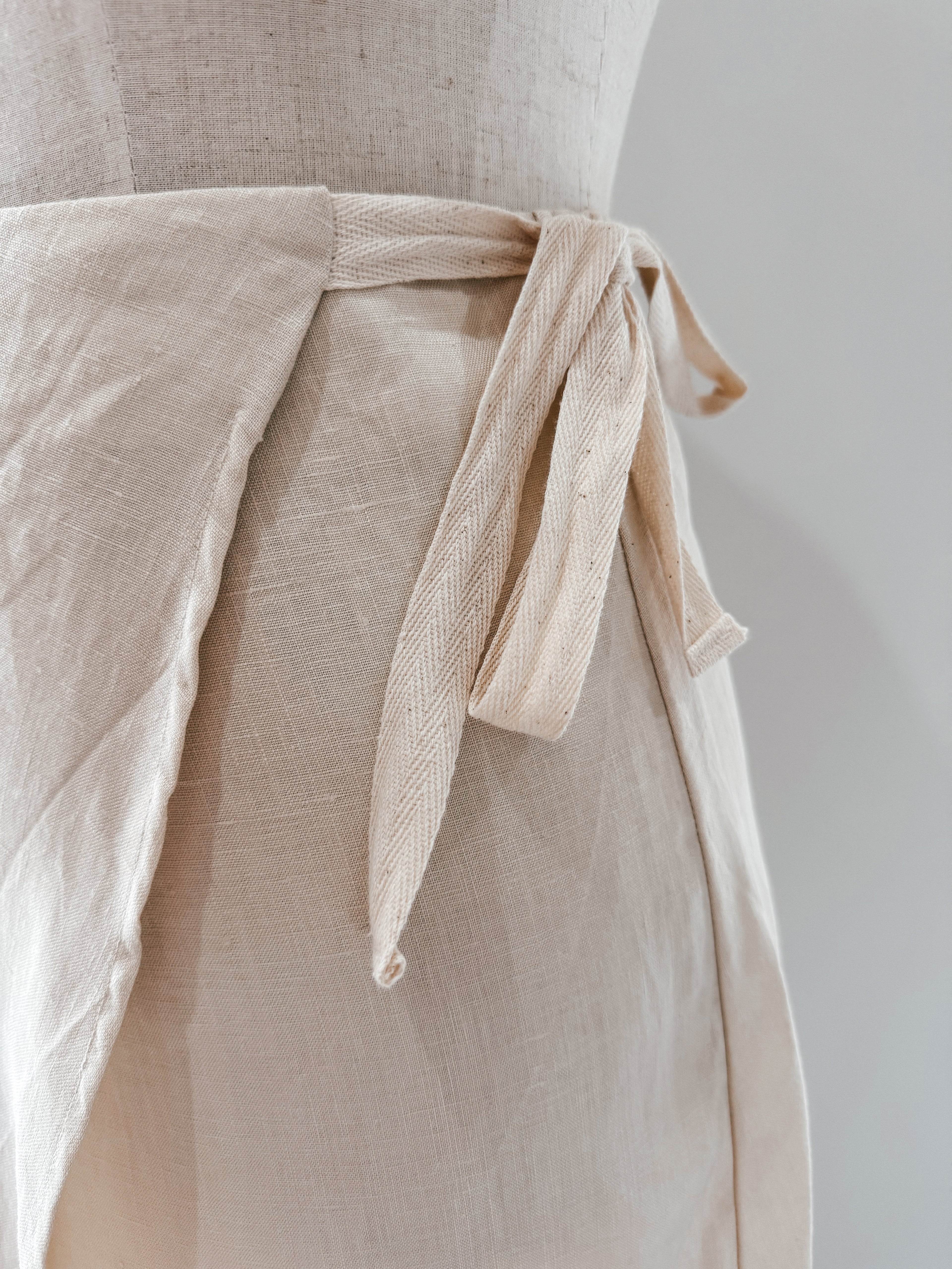 Close-up of natural twill tape side ties on wrap skirt  made from pure antique white colour pure linen.