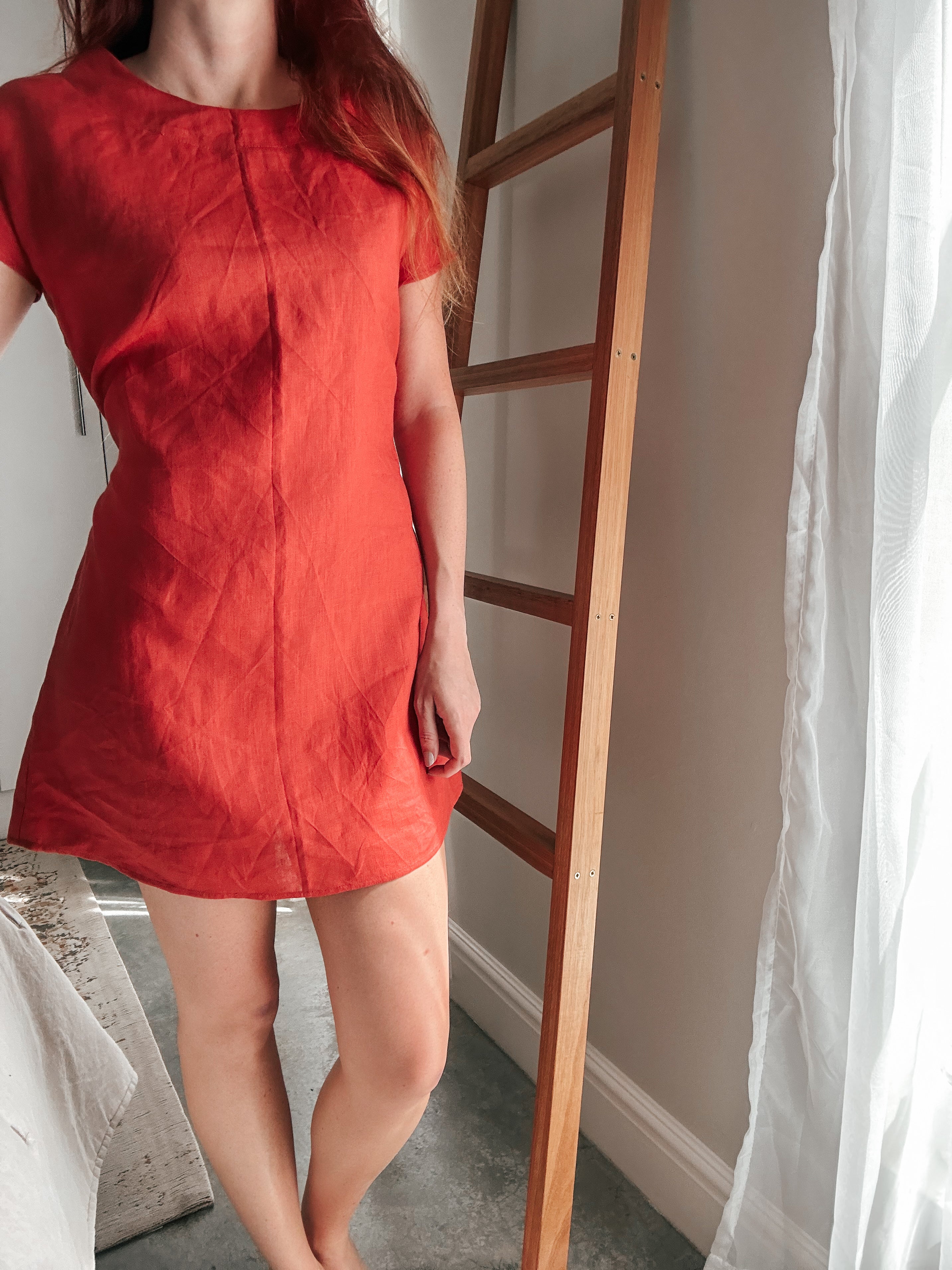 Person wearing a bright coloured pure linen tunic style dress in mini length with short sleeve.