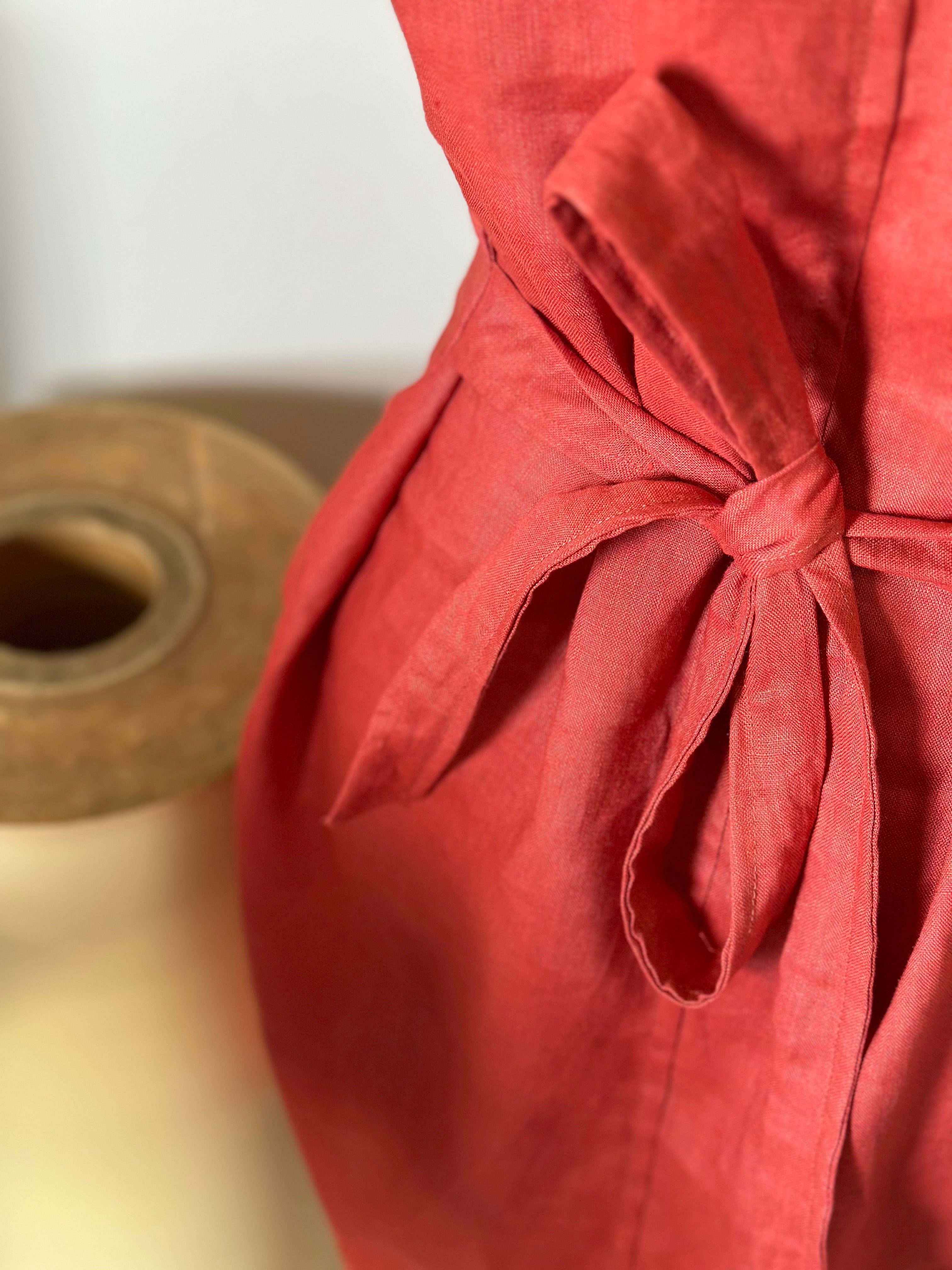 Close-up of a rust linen fabric dress with a bow.