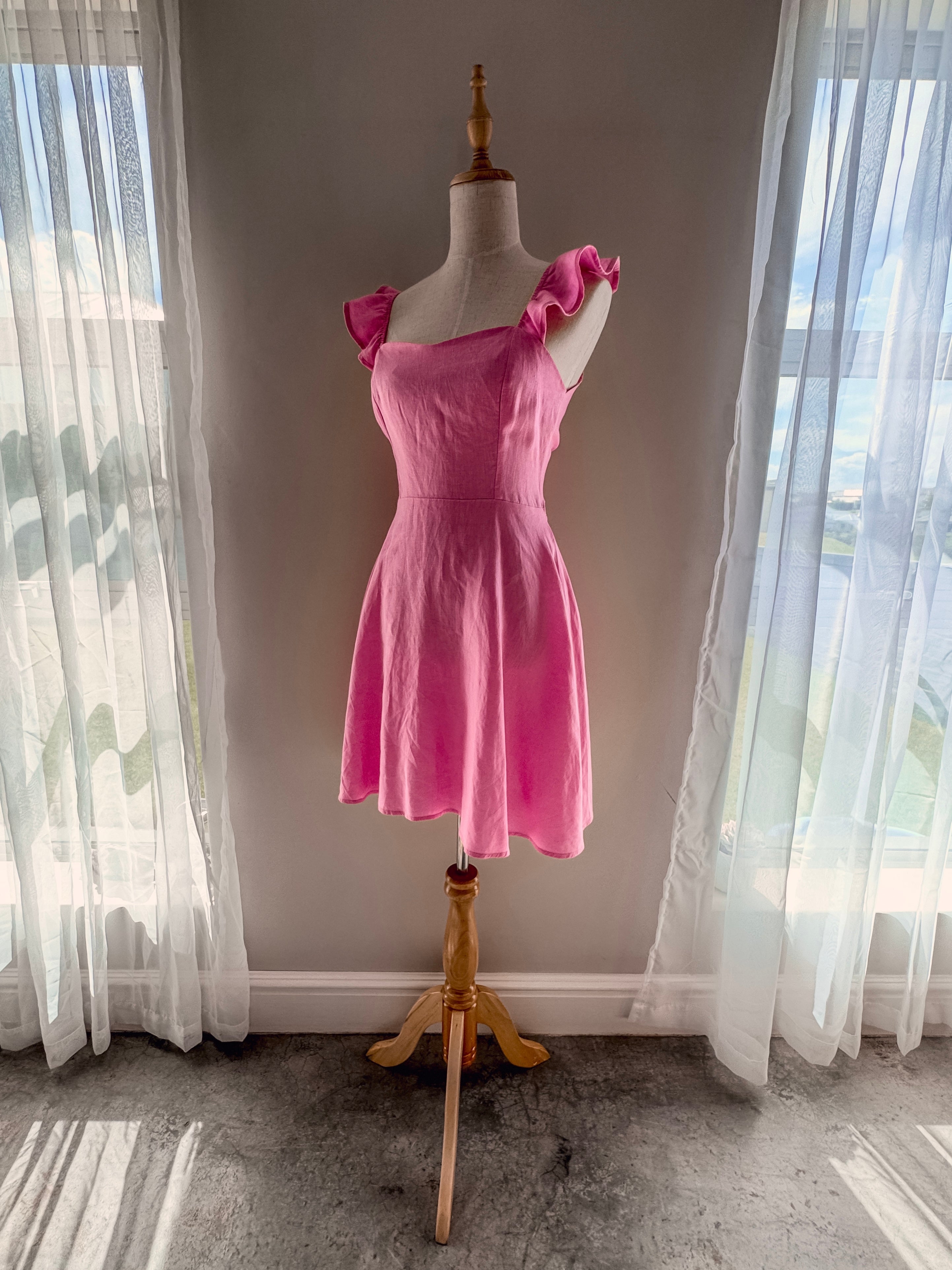 Candyfloss pink pure linen dress on a mannequin showcasing circle skirt section, corset upper body and frilly straps detail.