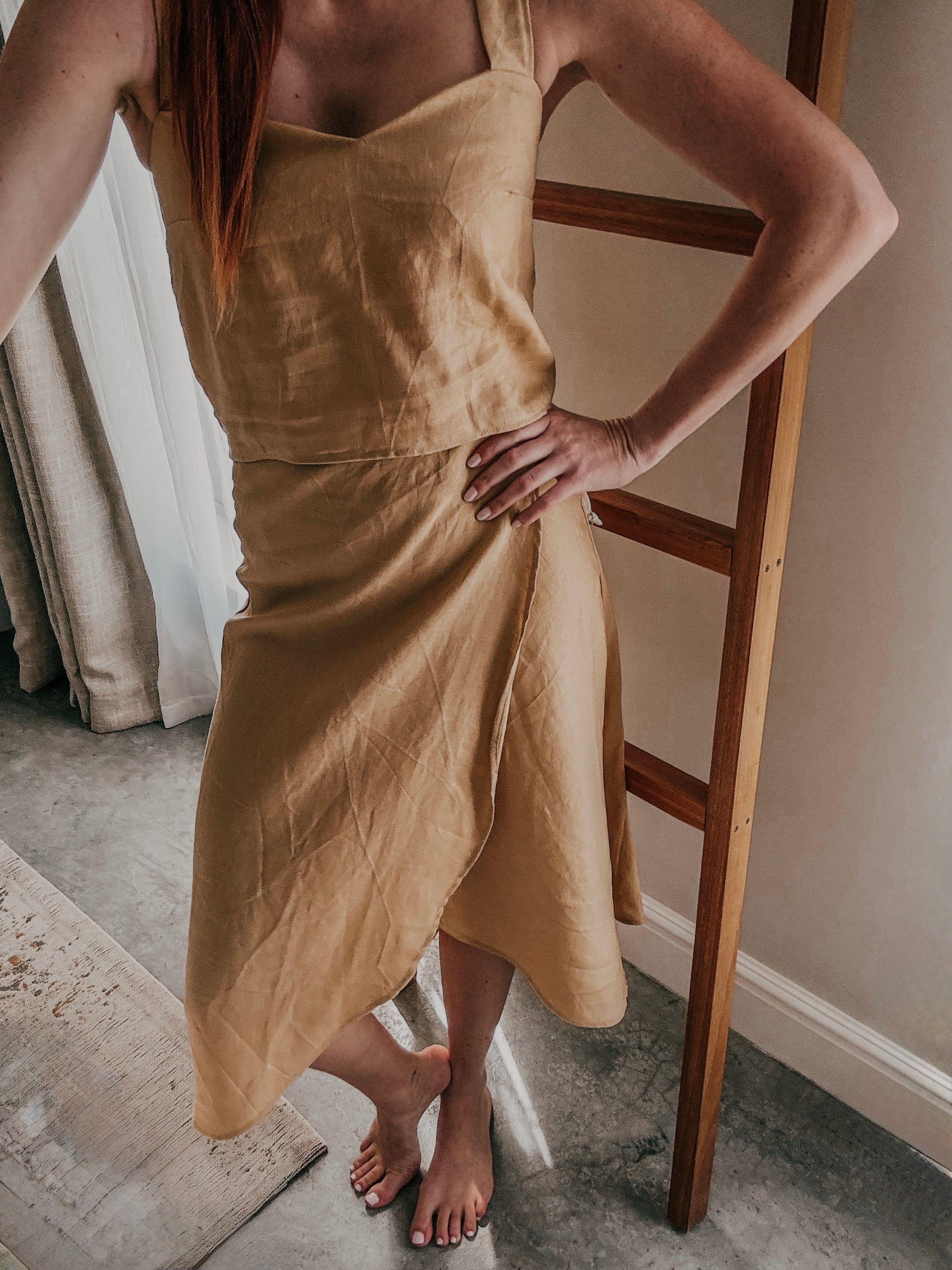 Woman standing wearing a beige matching wrap midi length skirt and cami top made from pure linen.