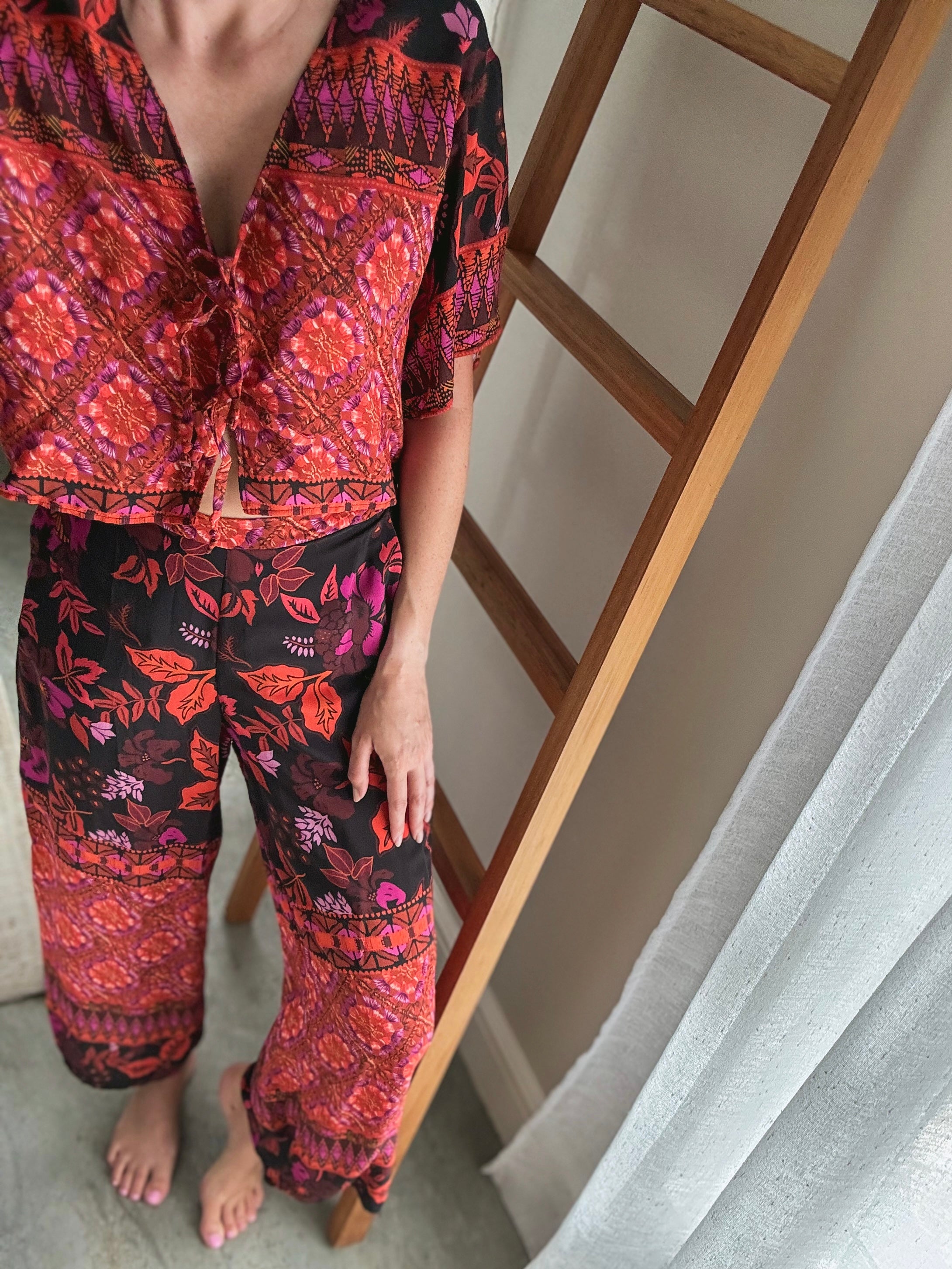 Person wearing a patterned long pants and front tie short sleeved top.