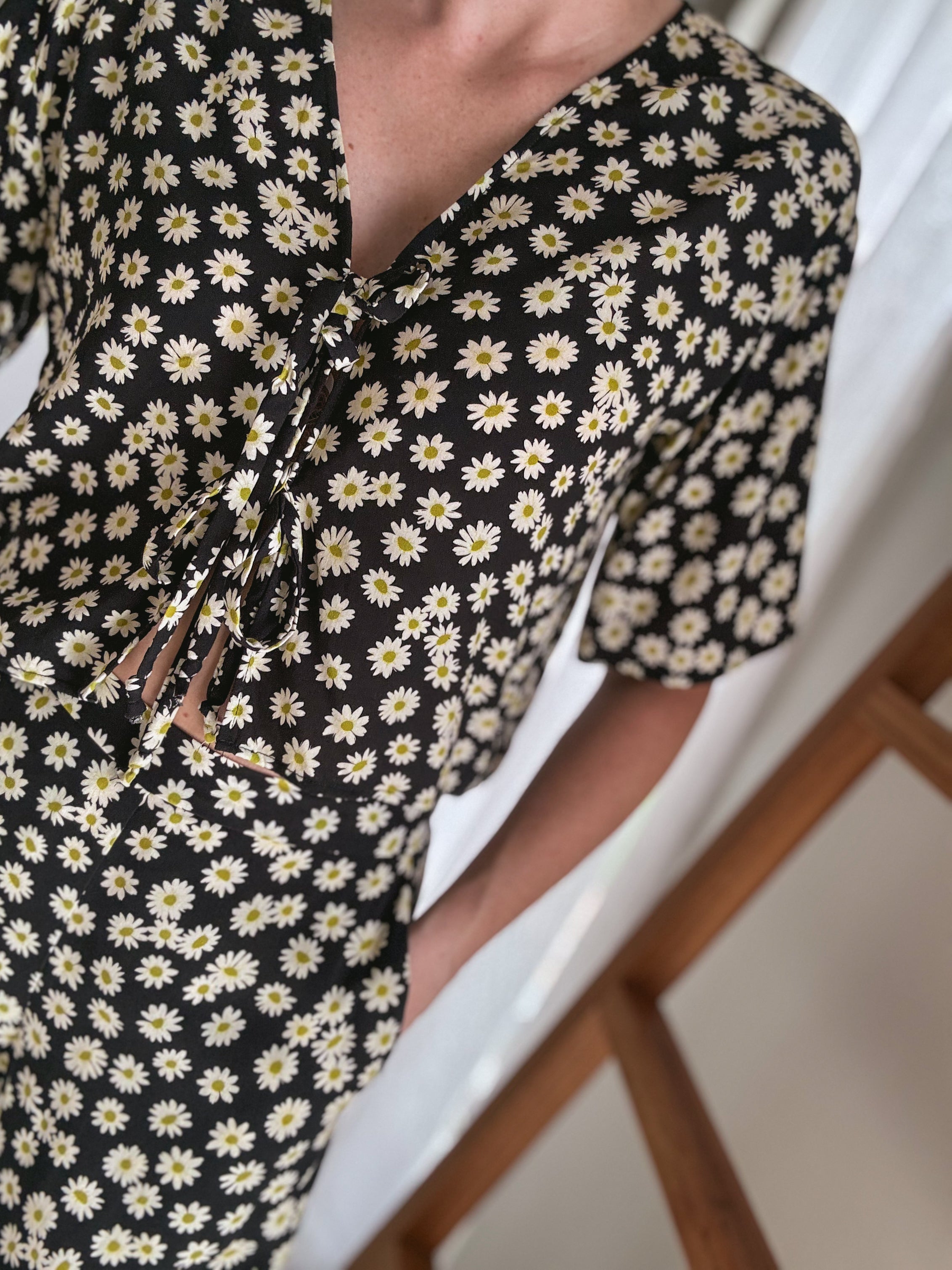 Close-up of a person wearing a daisy print set showcasing the front ties of the relaxed short sleeve top.