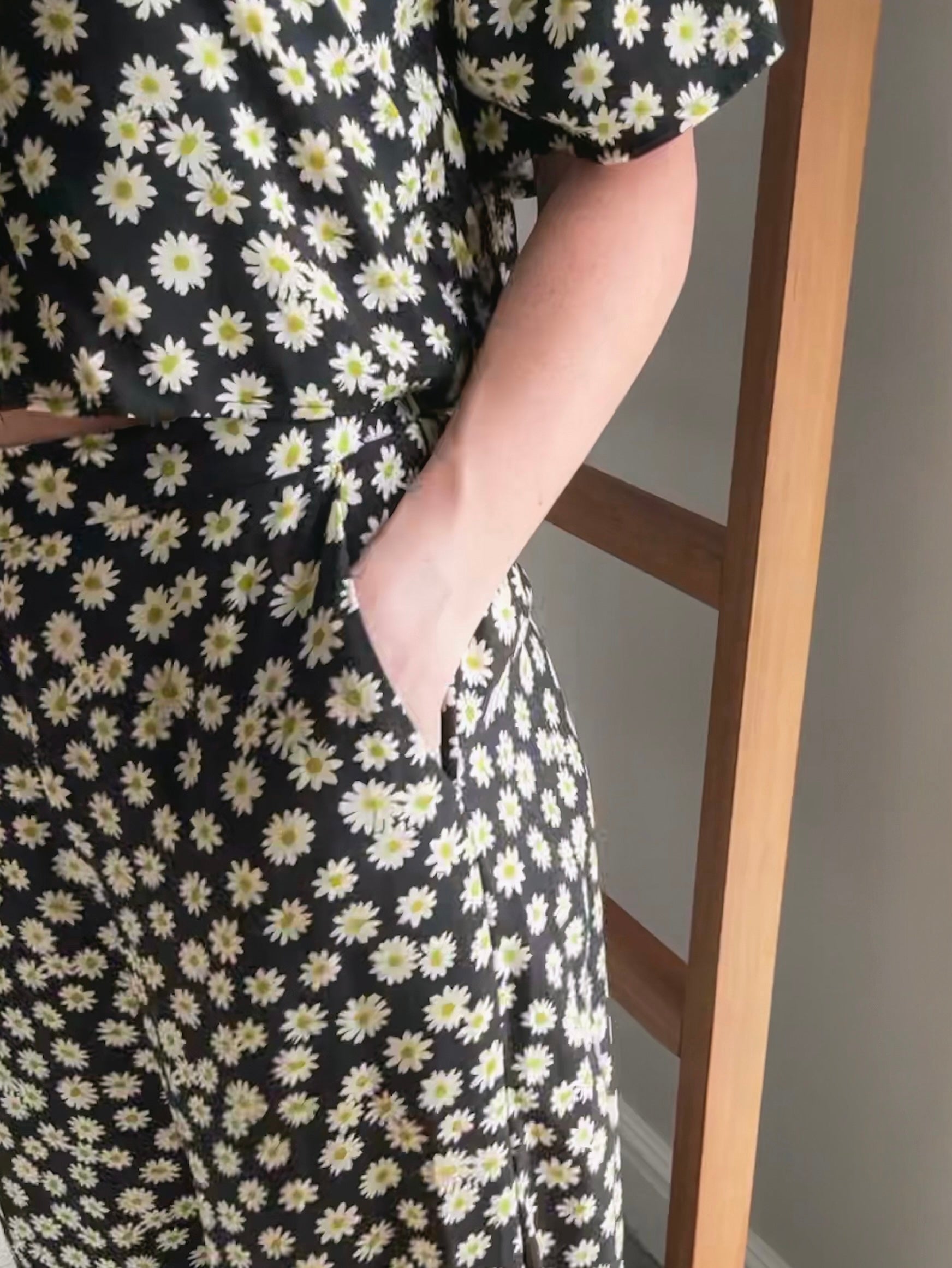 Close-up of hand in slanted pocket of pants while wearing daisy print set.