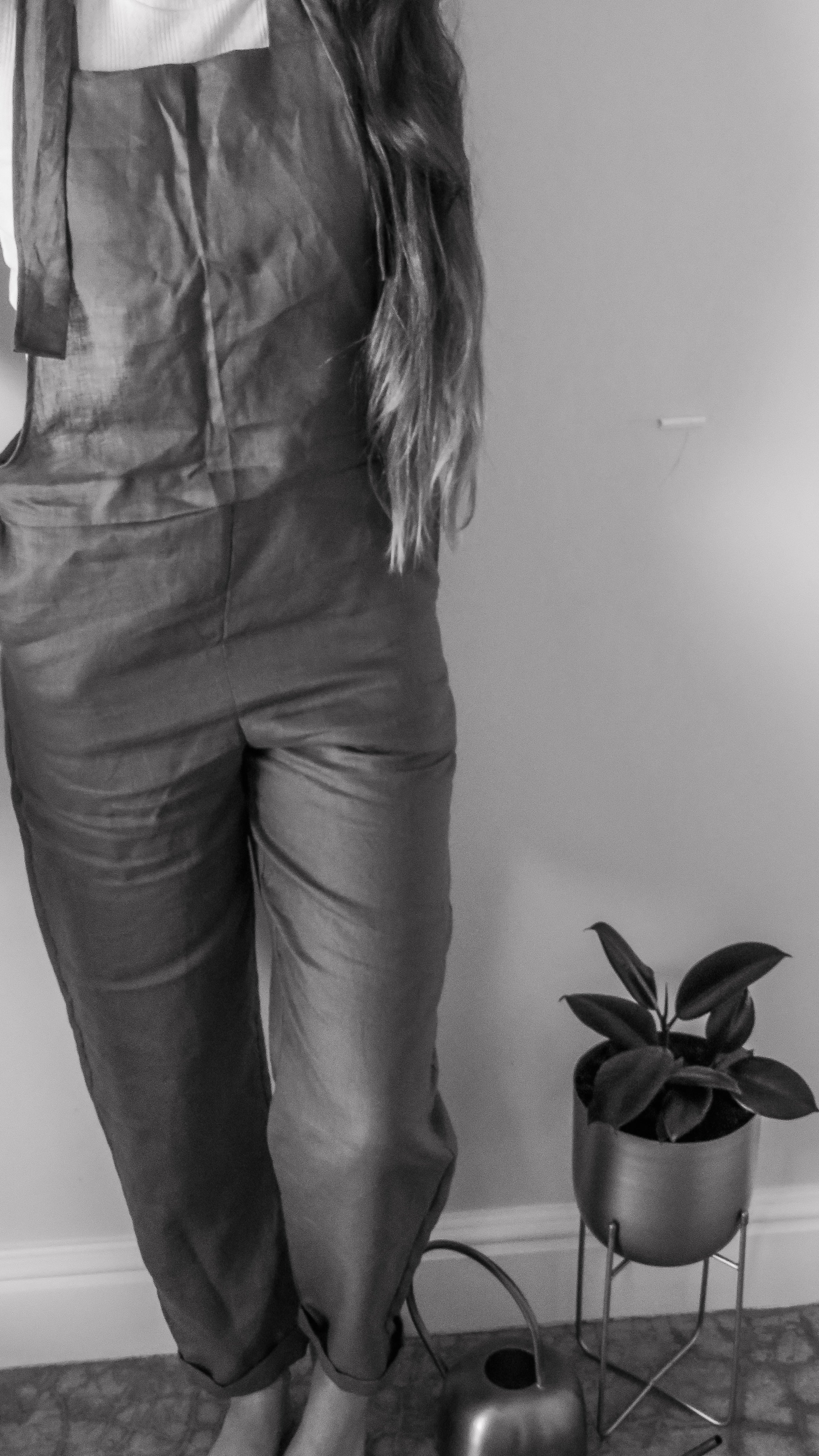Person wearing black dungaree overalls made from pure linen and adjustable straps.