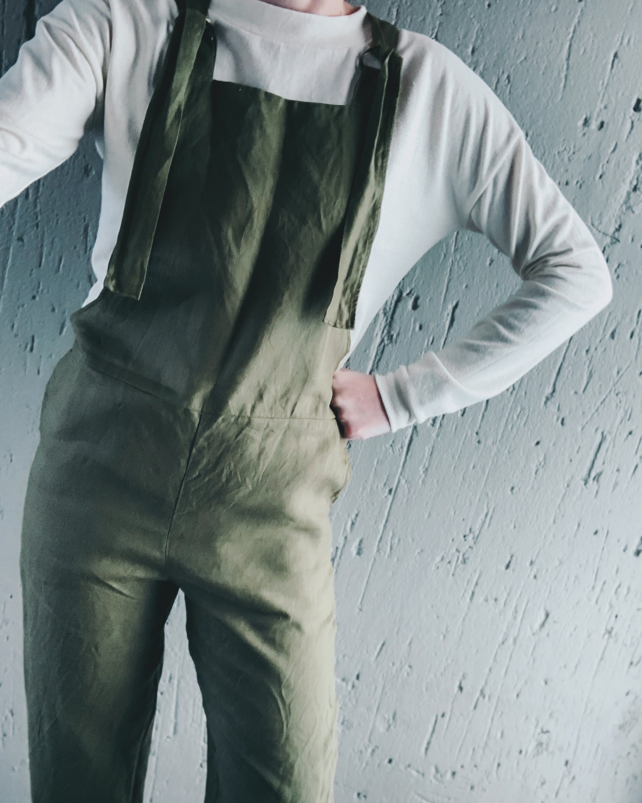 Person wearing olive green pure linen overalls paired with a long-sleeve shirt for Winter.