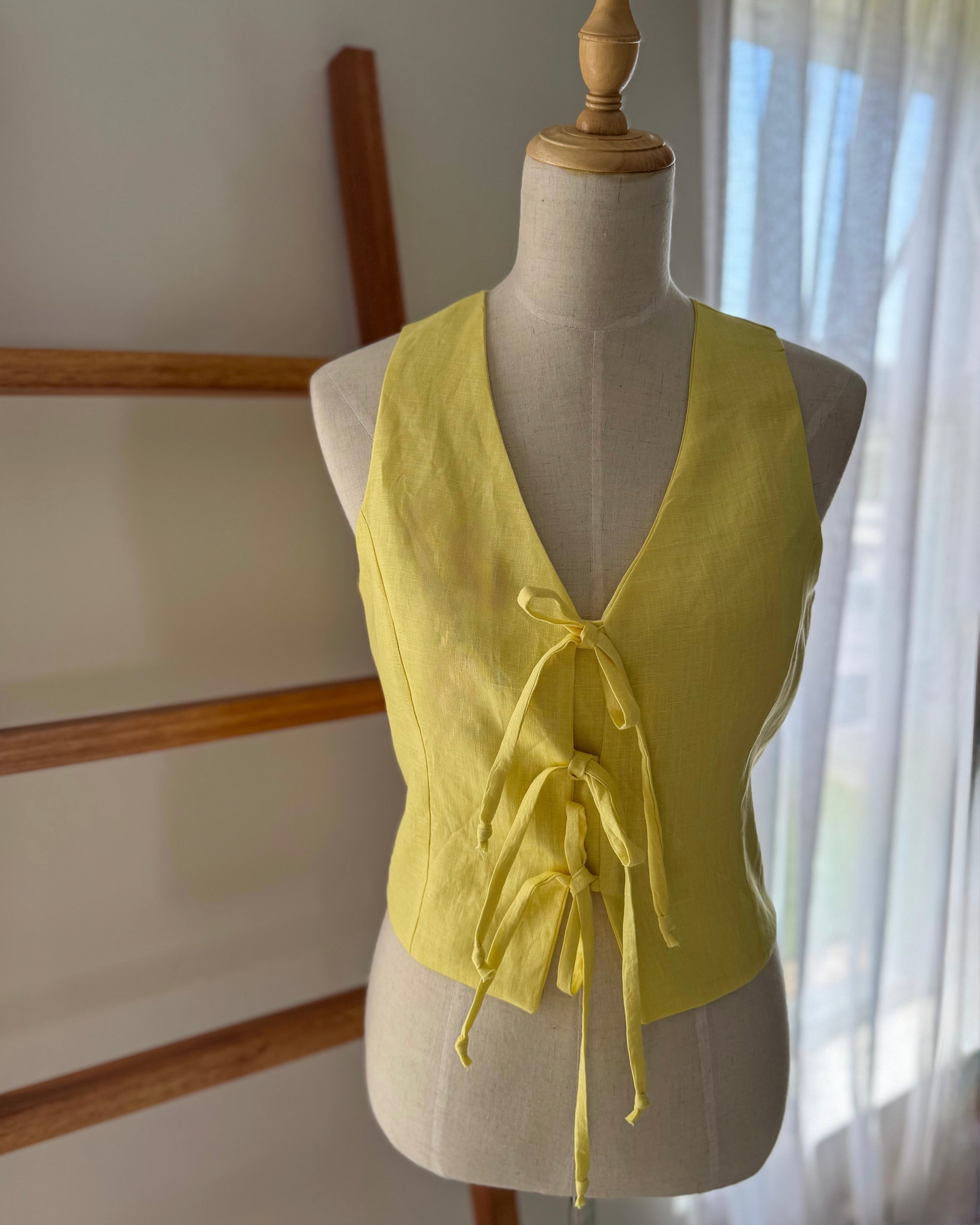 Butter yellow front tie waistcoat made from pure linen displayed on a mannequin.