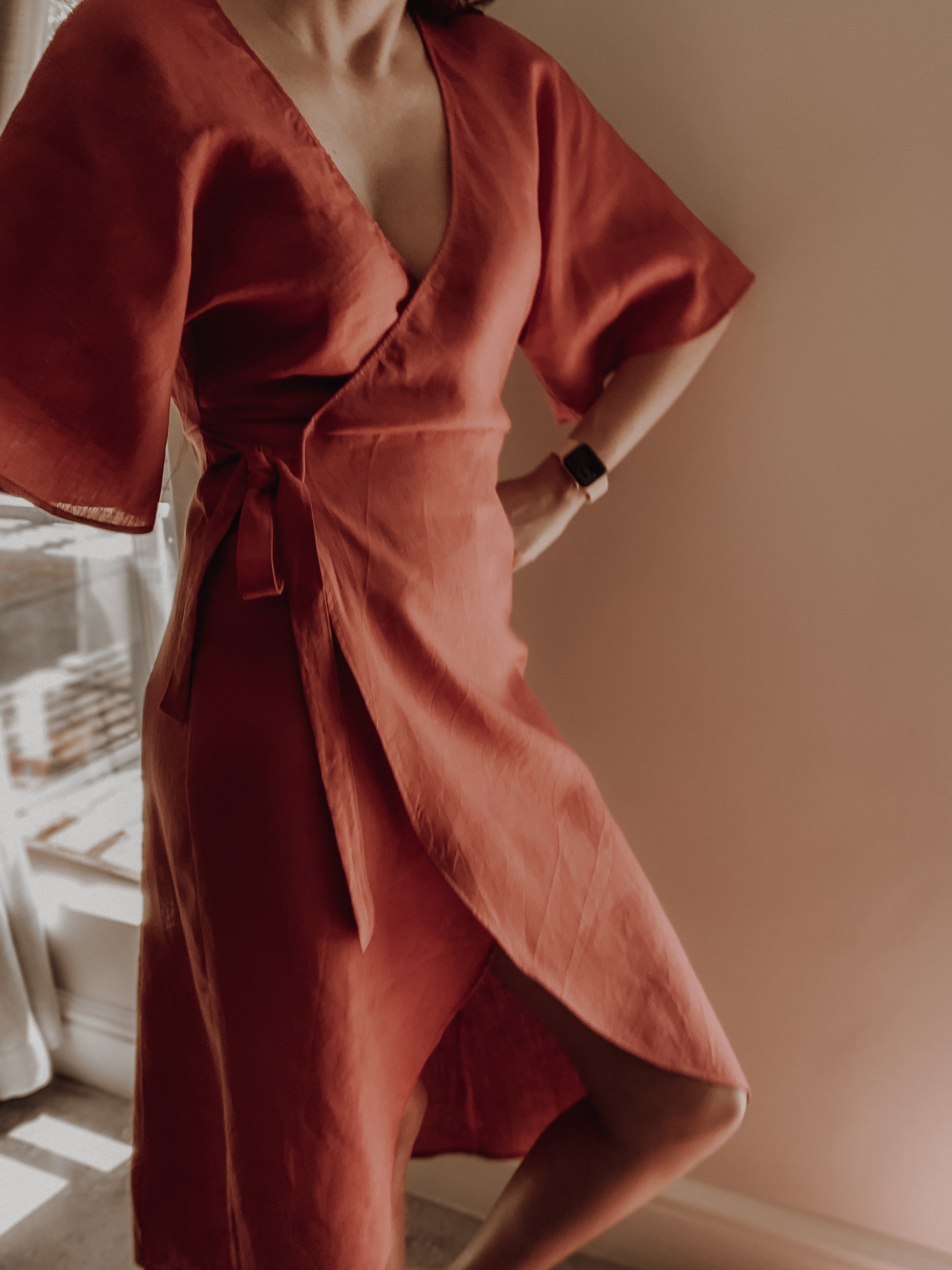 Women wearing a rust-coloured wrap dress with kimono sleeves and curved hem.