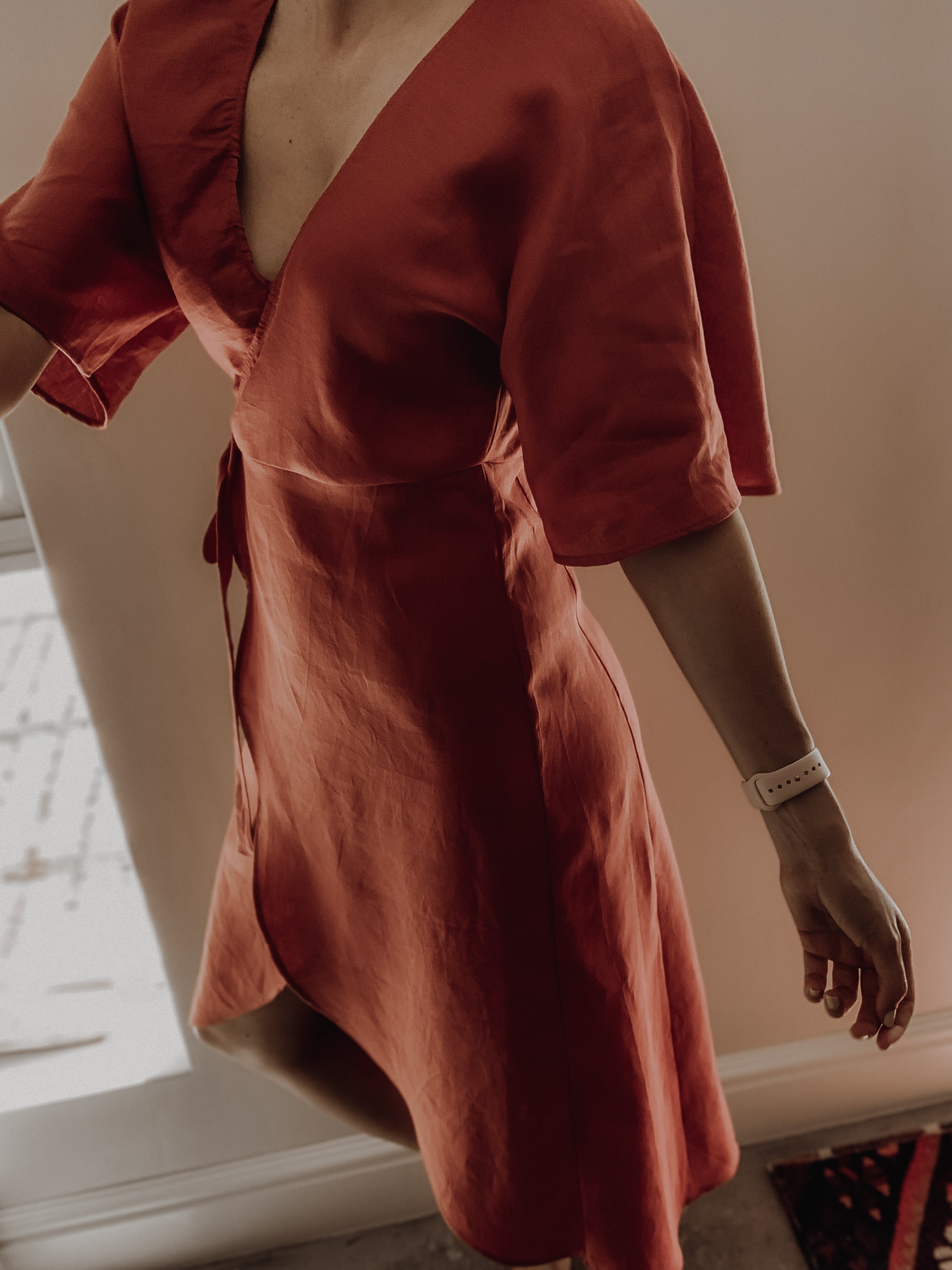 Person wearing a rust-coloured linen dress with curved hem.