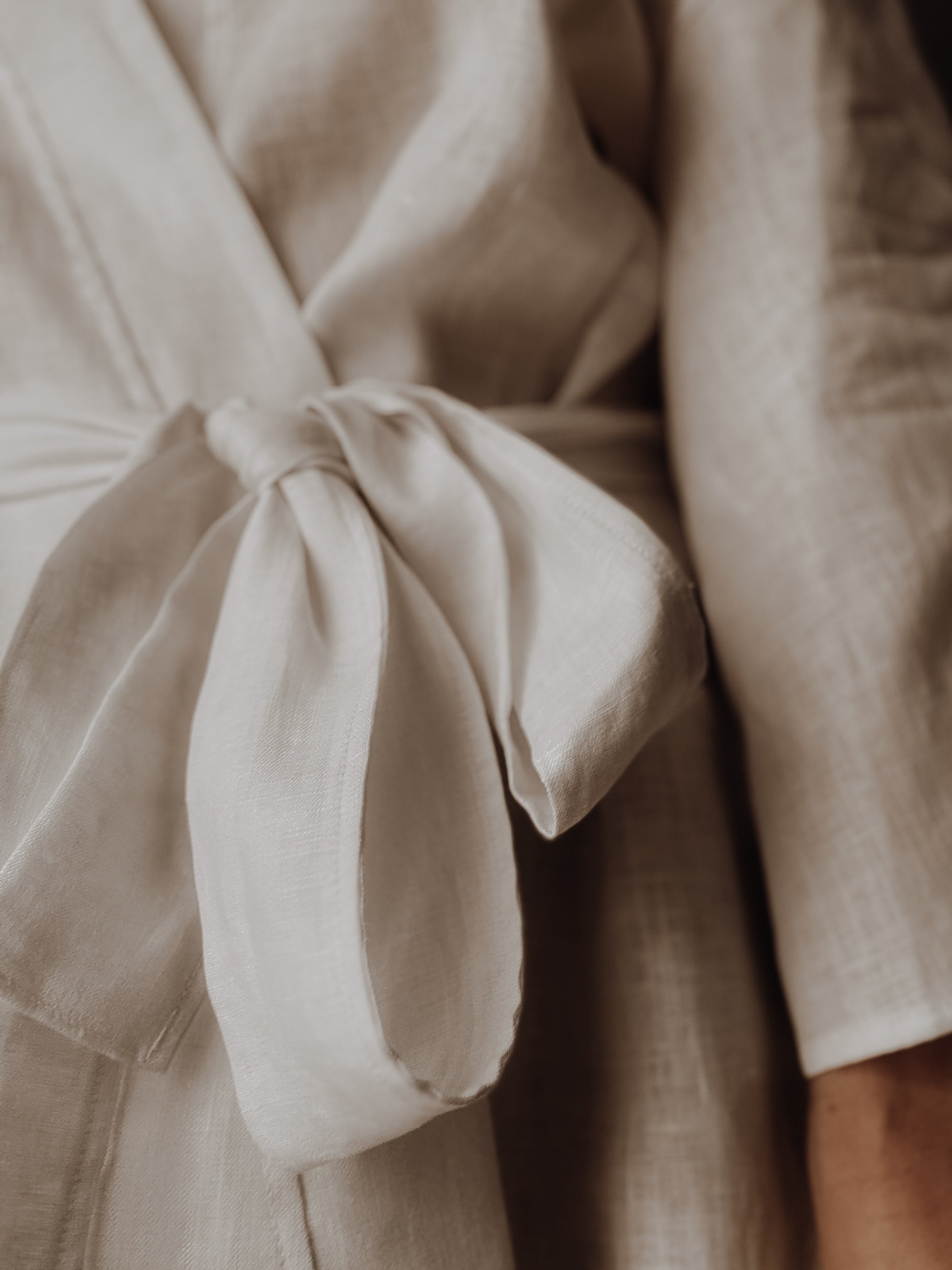 Close-up of white linen gown with a bow detail.