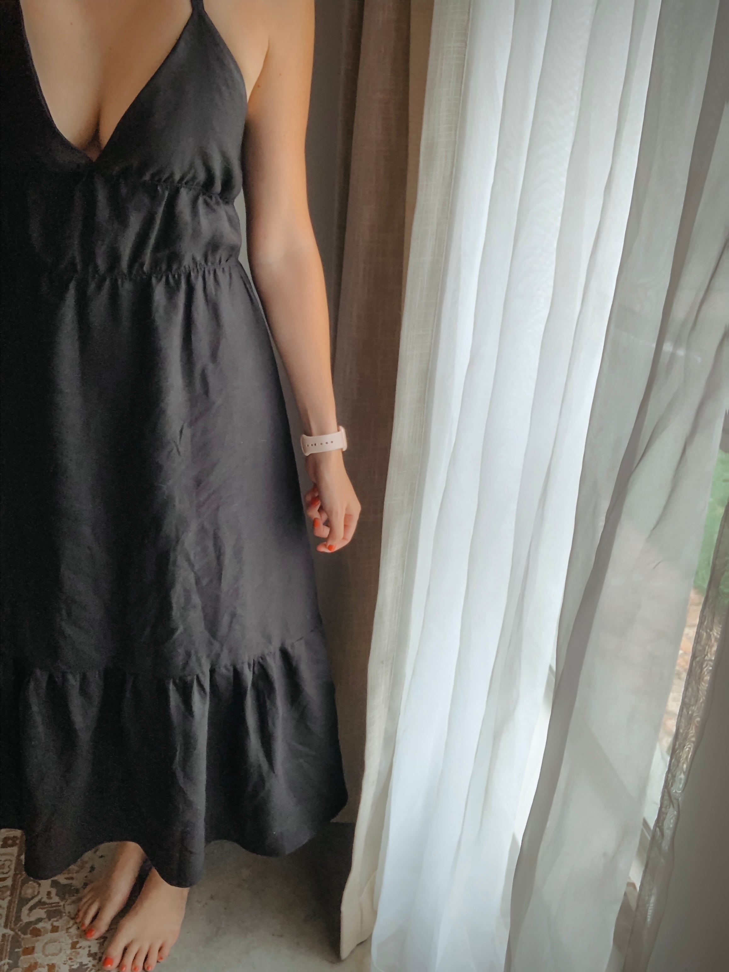Person wearing a black linen maxi dress standing in natural soft light.