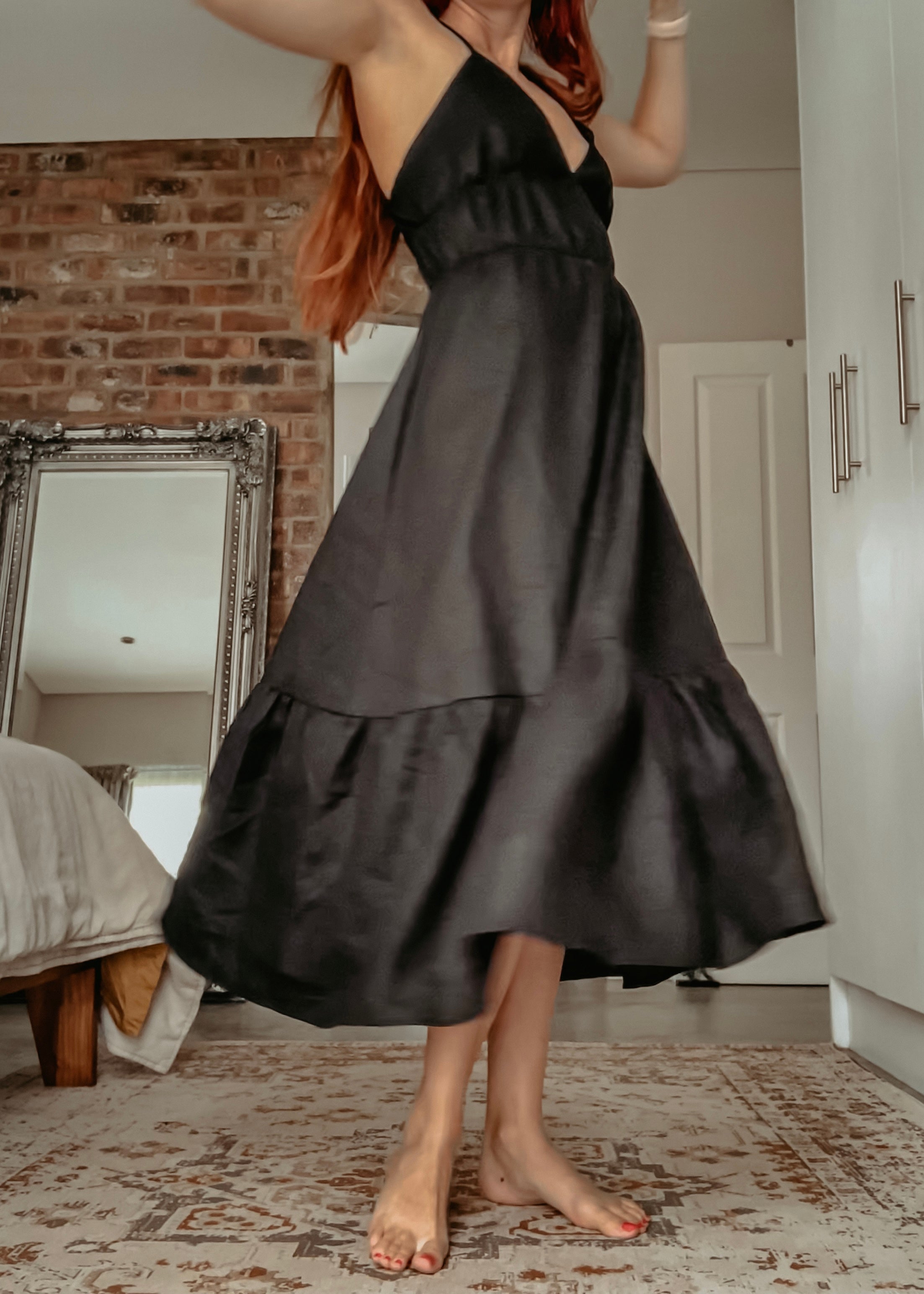 Person twirling in a pure linen black maxi dress with tiered sections.