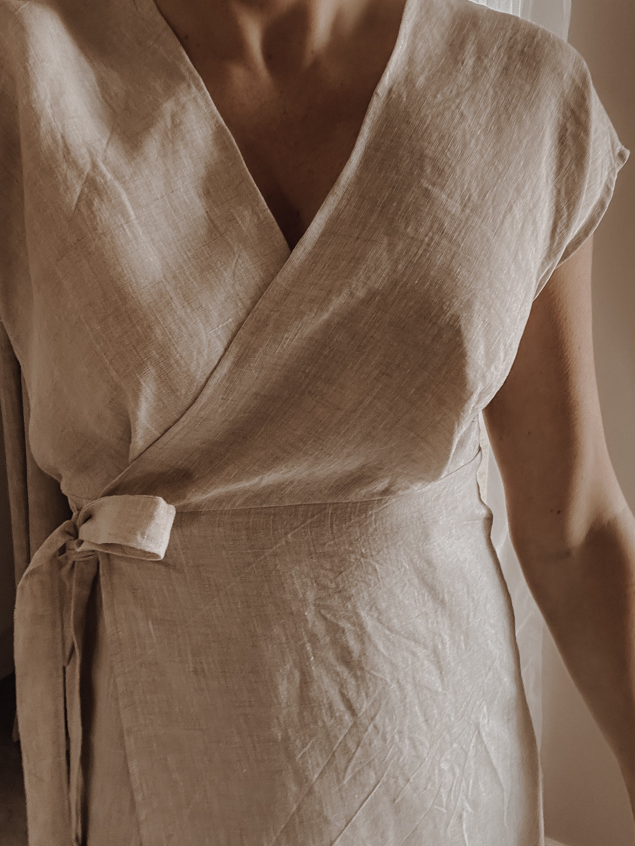 Close-up of a light beige linen wrap dress.