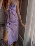 Person wearing a lilac colour milkmaid style dress with adjustable ruching detail at the front top, adjustable straps and front knee slit at midi length.
