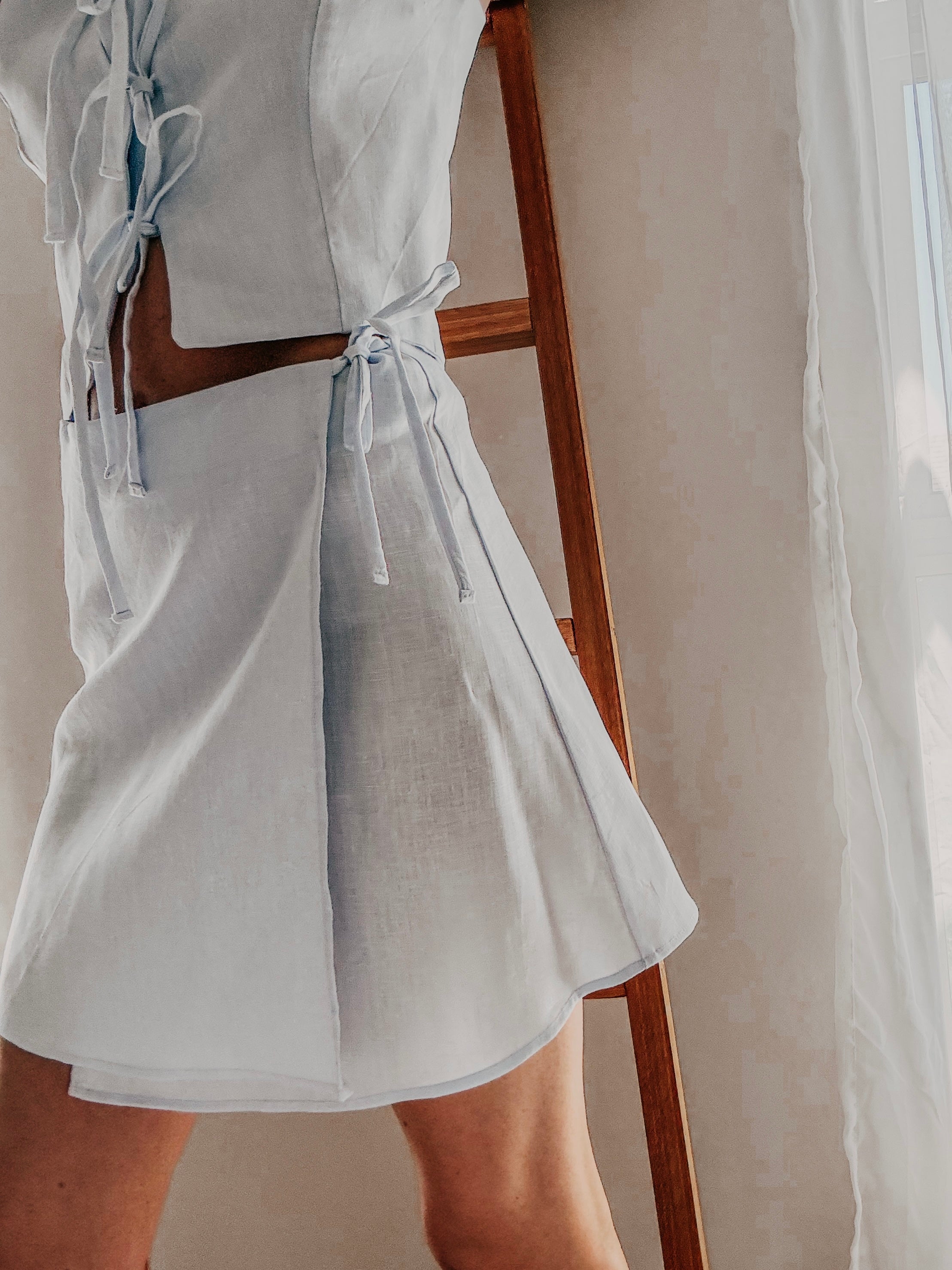 Side view of sky blue pure linen wrap style high-waisted mini skirt with side ties.
