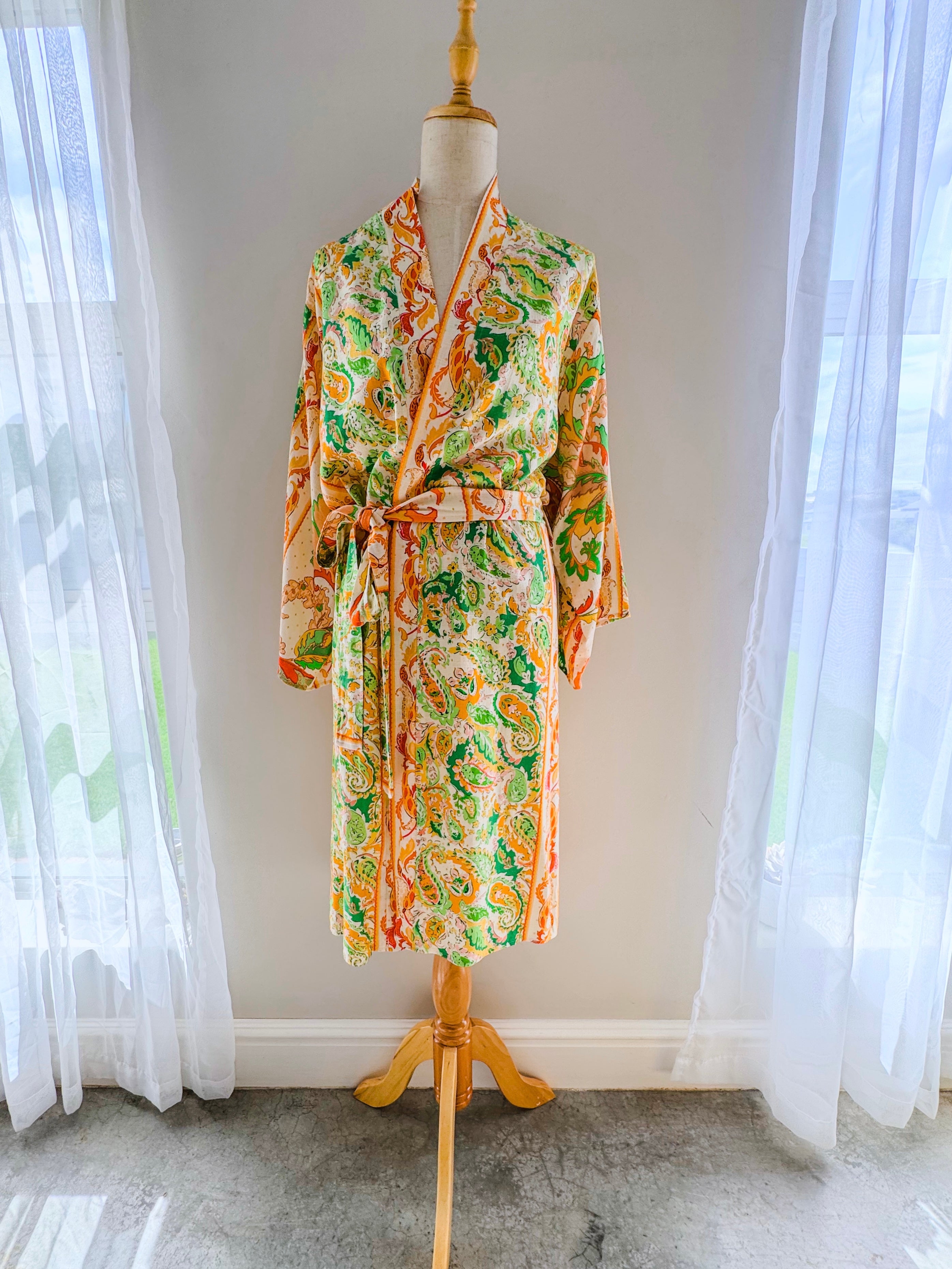 Colourful paisley patterned kimono gown in long length hanging open on a mannequin.