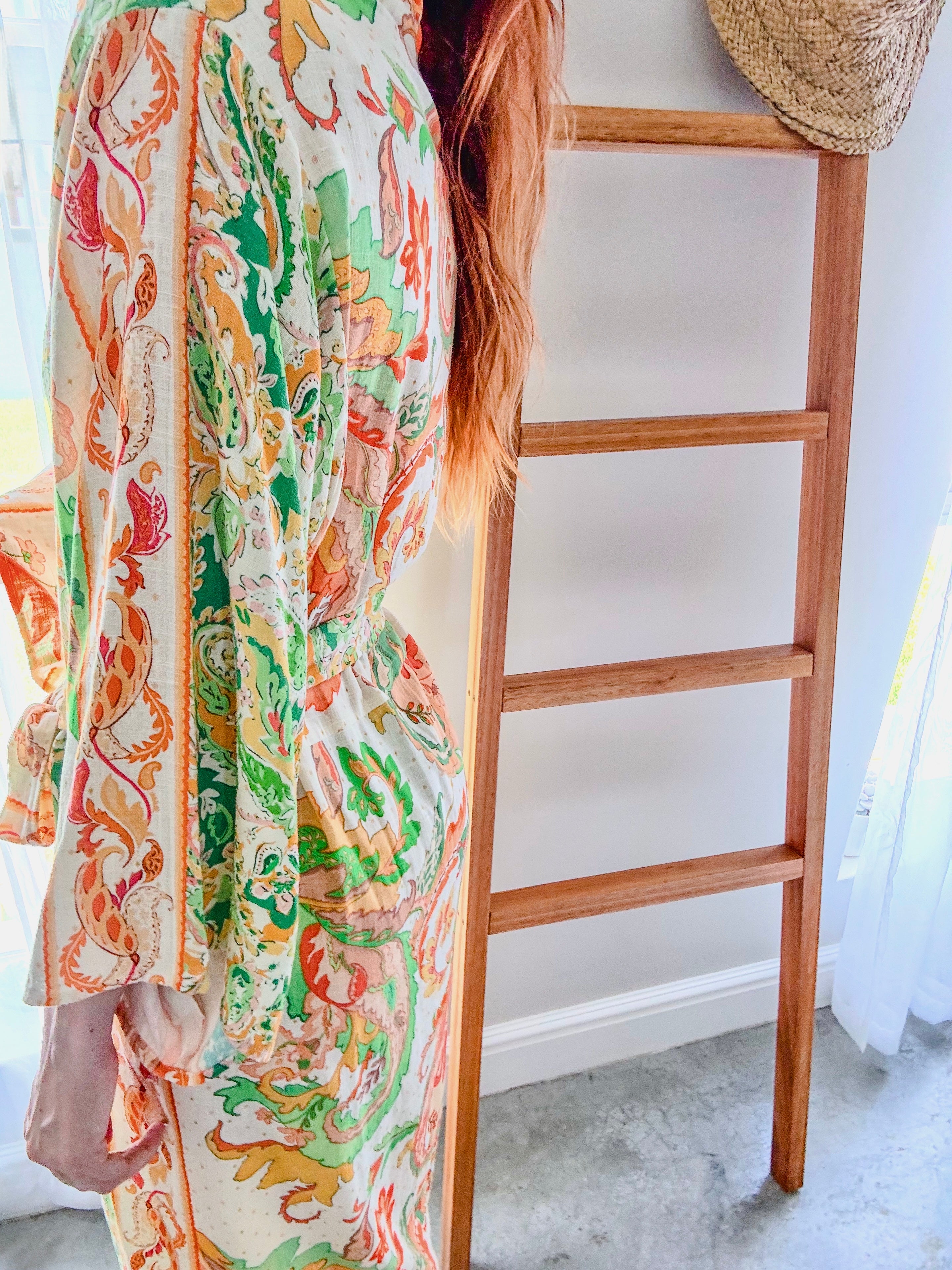 Side view of person wearing a long paisley print kimono gown in green and orange tones made from ecovero viscose linen.