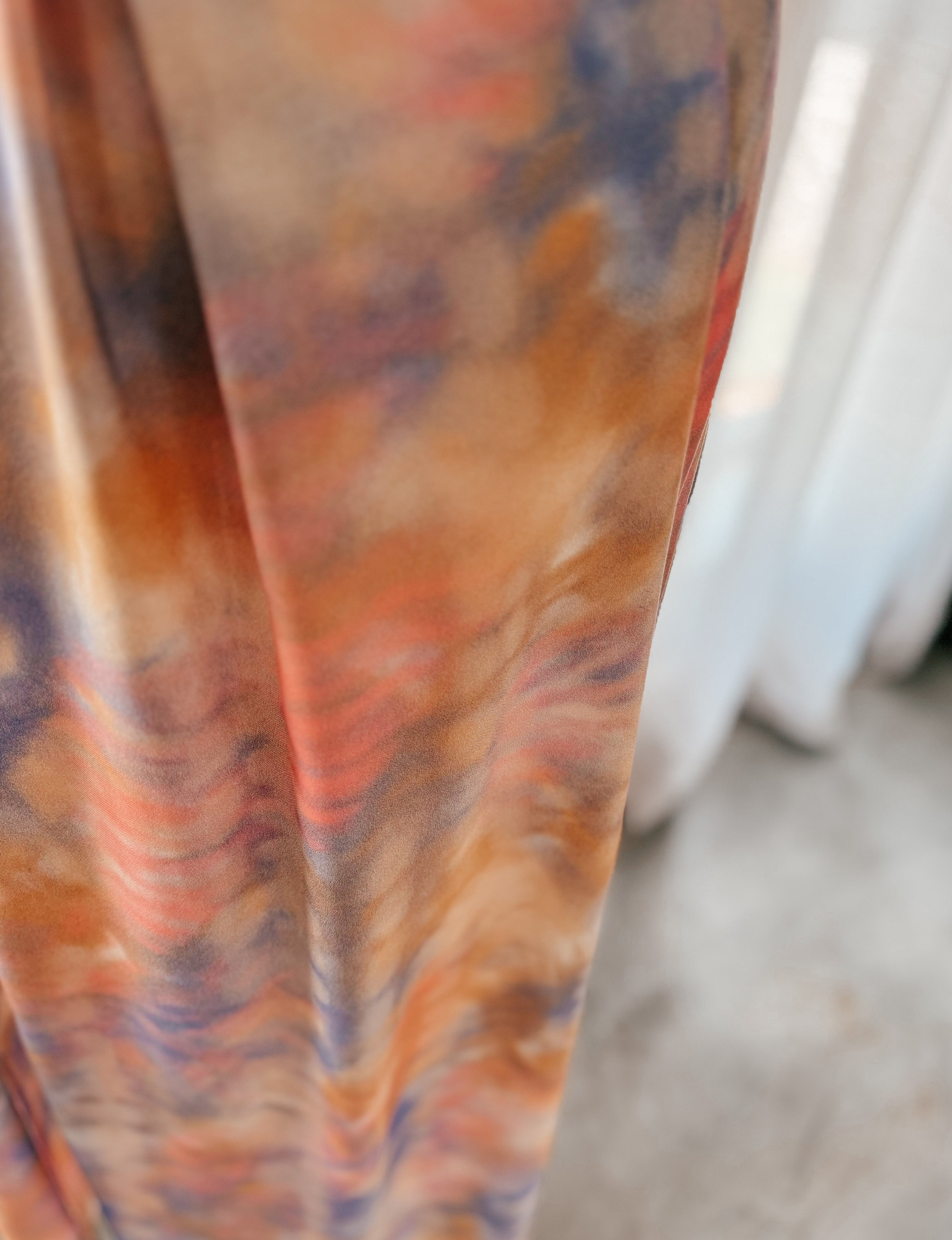 Close up of dress made from ecovero viscose fabric in tie-dye print of soft watercolour hues.