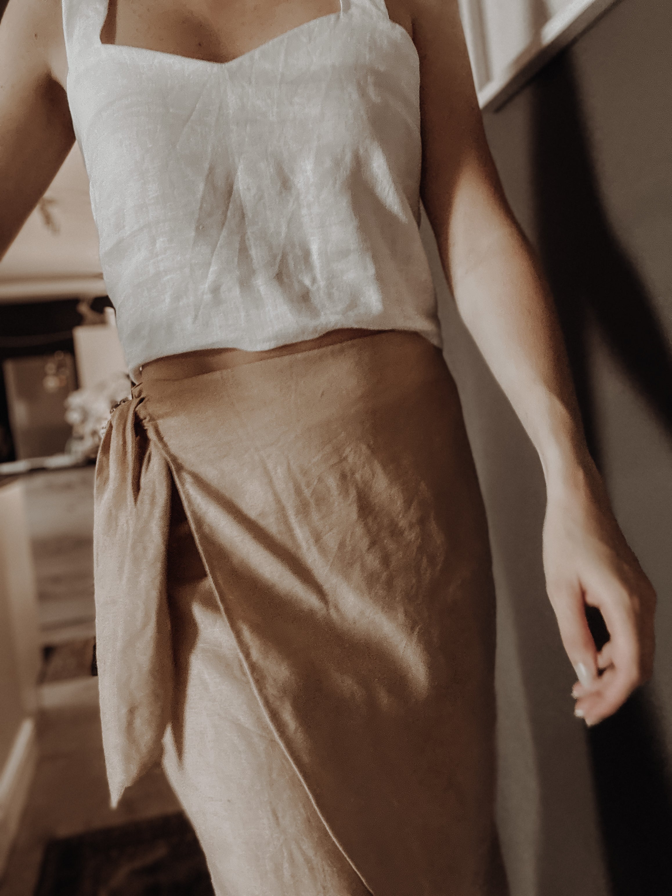Person wearing a sand colour high-waisted wrap skirt made from pure linen with lovely side knot detail.